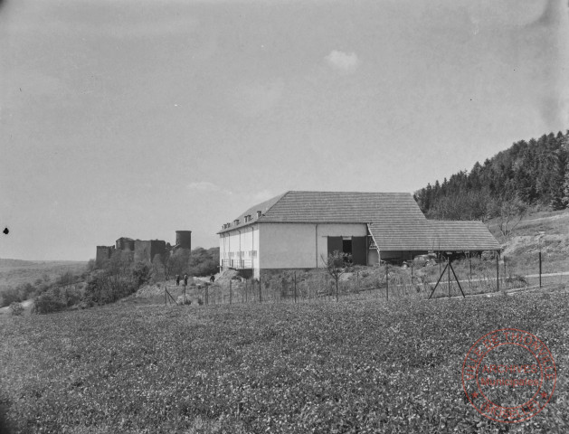 [Le château de Malbrouck (Manderen) en arrière-plan à gauche et un corps de ferme au premier-plan]