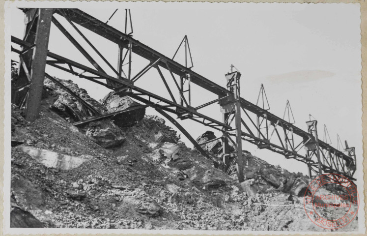 Parc à scories. Un aspect de la charpente dans la partie médiane. Scories pêle-mêle avec une énorme proportion de riquettes. Poteaux enlisés, arcs-boutants pliés.