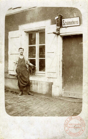 [Vue d'un cordonnier devant sa boutique vers 1900]