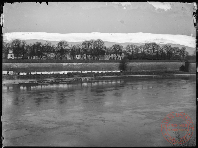 [Démantèlement des fortifications entre le pont et la place du Luxembourg. Au premier plan le linge des thionvillois lavé dans la Moselle est étendu le long du chemin de halage]