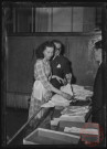 Foire exposition de 1948 - Un homme et une femme élue "Reine des sports" devant un étal de vêtements