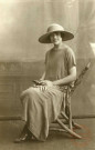 [Portrait d'une femme portant un chapeau, assise sur une chaise en bois]