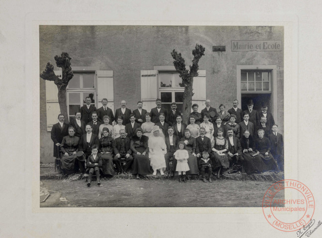 [Photo de groupe réalisée lors d'un mariage devant une mairie-école]