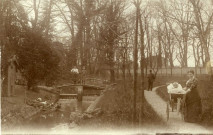 [Photographie d'un espace arboré avec une femme et son landau et deux jeunes filles sur un pont en 1909]