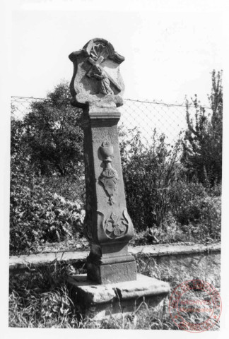 Bildstock situé à l'angle de la rue de Trèves et la route de Rodemack à Fixem. Croix érigée en 1769 (date portée sur le fût) pour Anne Tindingers. Portement de croix, calice, fleur de lys, feuillage, fleur