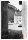 Vue depuis la ruelle au fond de la place de la Fontaine à Rodemack. Au fond la maison au 65 place de la Fontaine , puis le mur d'enceinte du château