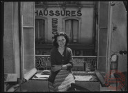 Foire exposition de 1948 - Femme posant sur une bordure de fenêtre. A l'extérieur on aperçoit un magasin de chaussures