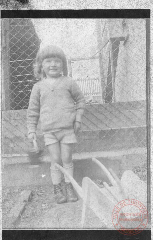Portrait d'une petite fille jouant avec un arrosoir et une brouette en bois