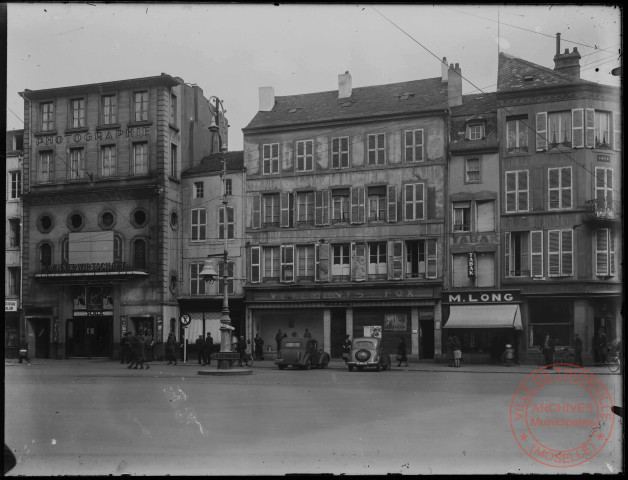 Place du Marché entre 1940 et 1944. Commerces : Photographie Schweisthal-Rodick, cinéma la Scala, vêtements Fox et tabac M. Long