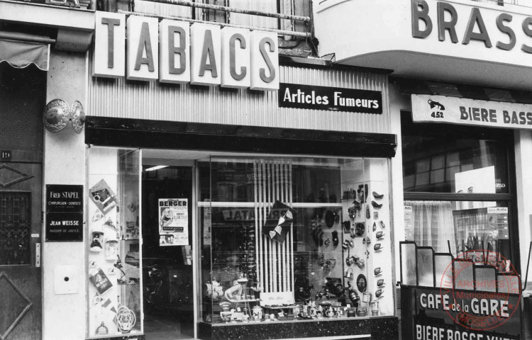 [Café de la Gare (Koelsch V.) 7 rue du Pont, tabac (Long V.) 17 place du Marché, à gauche 2 plaques, Fred Stapel chirurgien-dentiste et Jean Weisse huissier de justice au 19 place du Marché]