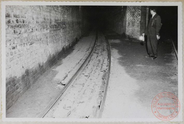 Galerie Charles. Le dallage recouvrant le caniveau a été cassé à la suite de déraillements et remplacé par des planches qui sont en mauvais état.