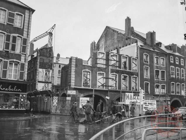 [Place du marché bâtiments de part et d'autre du croisement avec la rue Neuve. Chapellerie, bonneterie, chemiserie Foly-Flosse, magasin de cristaux et porcelaines et rénovation d'un immeuble]