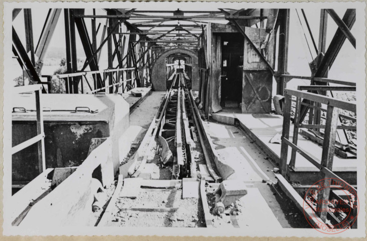Entrée du pont portique de stockage. Rupture, déformation et arrachement des contre-rails, cornières latérales de la chaîne. Déformation de la cabine de manœuvre. Vitres cassées remplacées par de la tôle ondulée, aplatie.