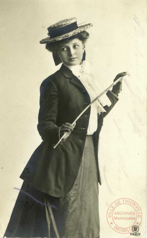 [Portrait d'une jeune femme portant un chapeau de paille et une petite canne élégante]