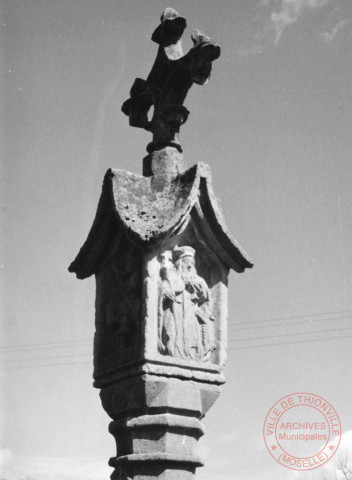 Bildstock à 4 faces situé rue Principale à Evange (commune de Breistroff-la-Grande). Croix érigée en 1540, attribuée à l'atelier de Ranguevaux, socle 19e siècle. Christ en croix ; Vierge ; saint Jean ; saint Antoine ermite ; saint Henri ; saint Hubert ; sainte Cunégonde ; symbole : religion chrétienne : croix ; symbole