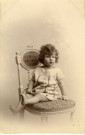 [Photographie d'une jeune fille assise sur une chaise]