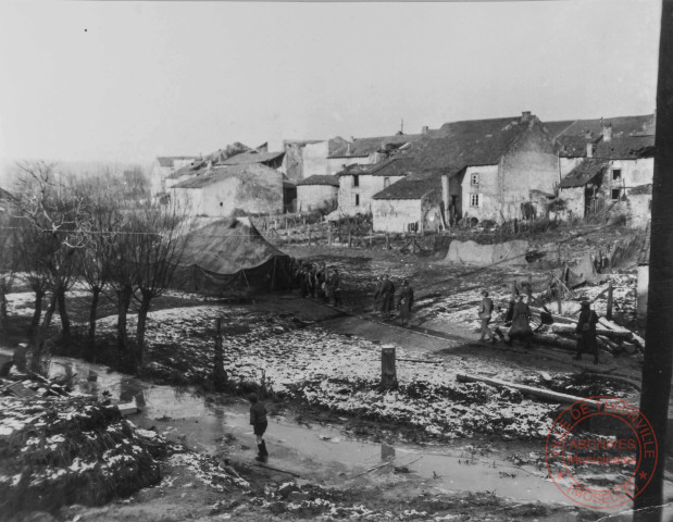 Malgré le frois, les Gi's prennent leur douche sous le regard indifférent d'un gamin qui patine sur le ruisseau gelé. Halstroff, en décembre 1944