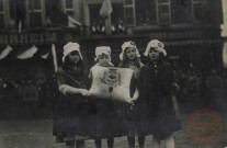[Remise de la Légion d'honneur à Thionville en février 1920. Quatre jeunes filles présentent la médaille sur un coussin aux armoiries de la ville]