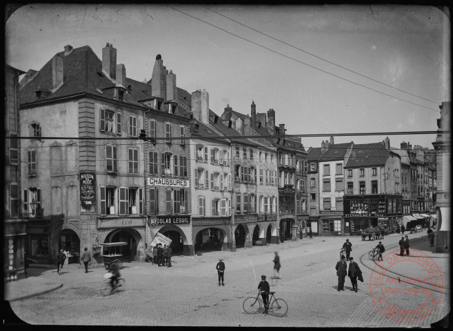 [Place du Marché et les arcades. Différents commerces," Les Eco", "Chaussures" Nicolas Leguil, une confiserie parisienne, Forfer-Oury, Léon Séquer, cinéma "La Scala", une épicerie et "Au grand bazar" Sternheimer frères]