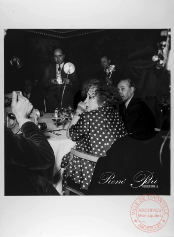 Prix Goncourt 1949 : L'écrivain COLETTE, membre du jury du prix Goncourt arrive au restaurant Drouant. Le jury réunit autour d'une table est entouré par les photographes.