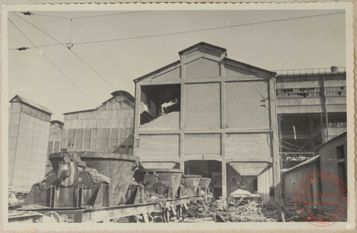 Silos à chaux. On voit le pan de mur du pignon sud démoli par obus après le 1er octobre 1944 et par la brèche on distingue un des trous dans la toiture. On a aussi une petite idée de l'encombrement des voies à la partie inférieure, bien que le nettoyage soit déjà avancé au moment de la photo.