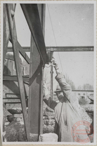 Brise fonte. Le chemin de roulement du pont n'est plus de niveau et le fil à plomb indique que le poteau voisin n'est plus vertical. Les fondations ont cédé sous la charge des loups accumulés dans cette halle. Elle était déjà à peu près déblayée au moment de la prise de vue.