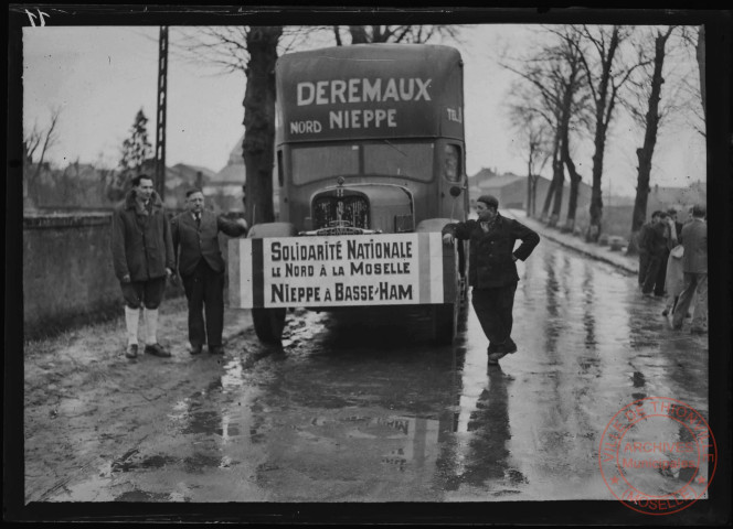 Foire exposition de 1948 - Autorités civiles à côté d'un camion de transports "DEREMAUX". Pancarte "Solidarité Nationale, le Nord à la Moselle, Nieppe à Basse-Ham"