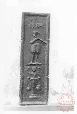 Taque en fonte datée 1584, au presbytère de Cattenom, rue des Châteaux. Scène d'un musicien avec une flûte à bec