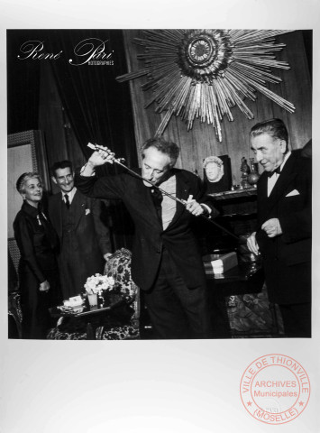 Portrait de Jean Cocteau avec son épée d'académicien. Jean Lacouture au fond
