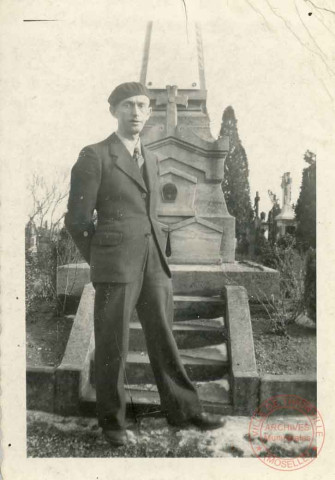 Portrait d'un homme en béret posant devant une stèle ou monument aux morts