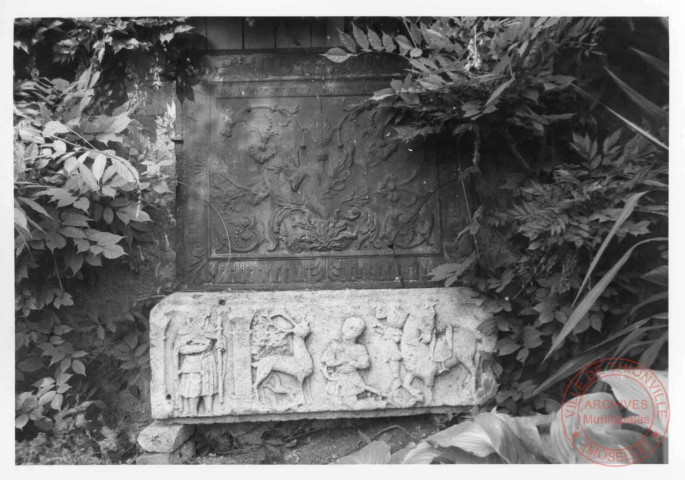Demi-relief placé 1 rue de la Fontaine à Cattenom. Sculpture en calcaire taillé, il représente un scène historique (Saint-Hubert : vision, cerf, chien, cheval, homme)