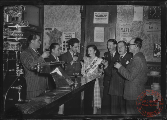 Foire exposition de 1948 - La "reine des sports 1948" accompagnée par les autorités civiles, trinquant dans un bar thionvillois