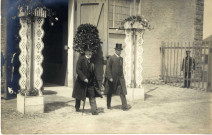 [Photographie de deux hommes en haute forme sortant d'un bâtiment de la foire exposition de 1914]