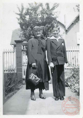 Portrait d'un jeune garçon et sa grand-mère dans la cour d'une maison