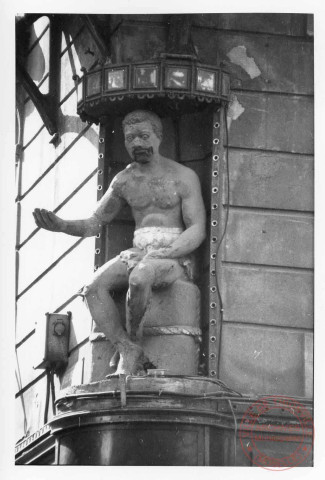 Statue représentant un homme assis sur un ballot de tabac, située à l'angle de la rue des Deux-Places et de la rue du Four Banal à Thionville