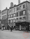 [Place du marché bâtiments de part et d'autre du croisement avec la rue Neuve. Chapellerie, bonneterie, chemiserie Foly-Flosse, magasin de cristaux et porcelaines et rénovation d'un immeuble]