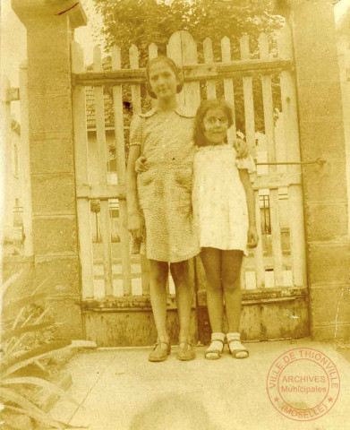 2 jeunes filles posant dans la cour d'une maison