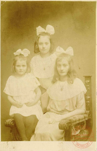 3 jeunes filles portant une robe blanche et un flot blanc posent en studio