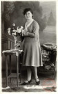 [Portrait d'une femme arrangeant un bouquet de fleurs dans un vase posé sur un guéridon]