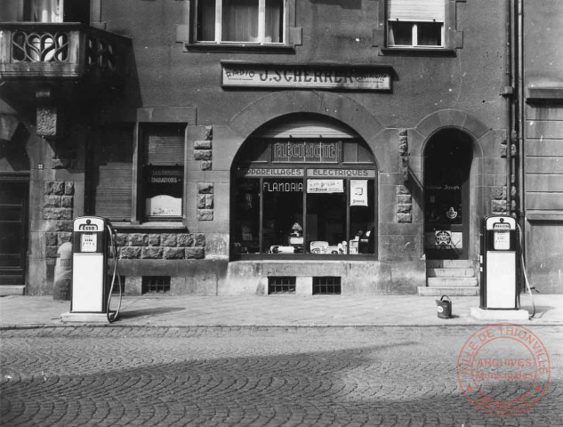 [Magasin J. SCHERRER, appareillages électrique au 22 rue Albert 1er, deux pompes essence devant la boutique]