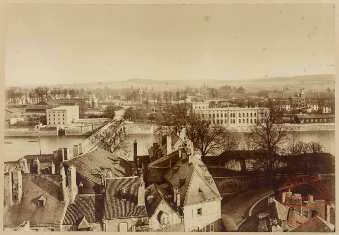 [Vue en hauteur prise depuis le Beffroi vers la rive droite de la Moselle, vers le quartier gare. On y voit l'ancien hôpital militaire, la gare, le pont, les remparts]