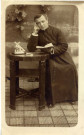 [Photographie d'un prêtre attablé avec un livre à la main en 1915]