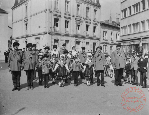 [Groupe folklorique place Claude Arnoult, lors d'une commémoration. En arrière-plan, porte-drapeaux et musique des sapeurs-pompiers]