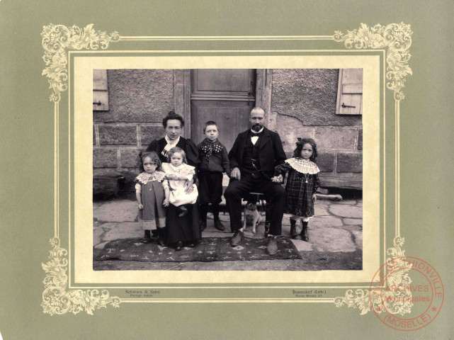 [Photographie d'un couple posant devant le pas de porte avec leurs enfants dans les années 1900]