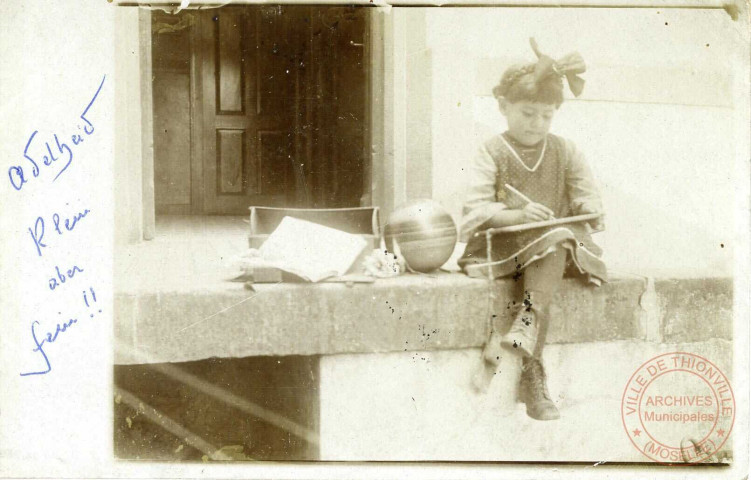 [Portrait d'une petite fille studieuse, avec un flot dans les cheveux et tenant une ardoise]