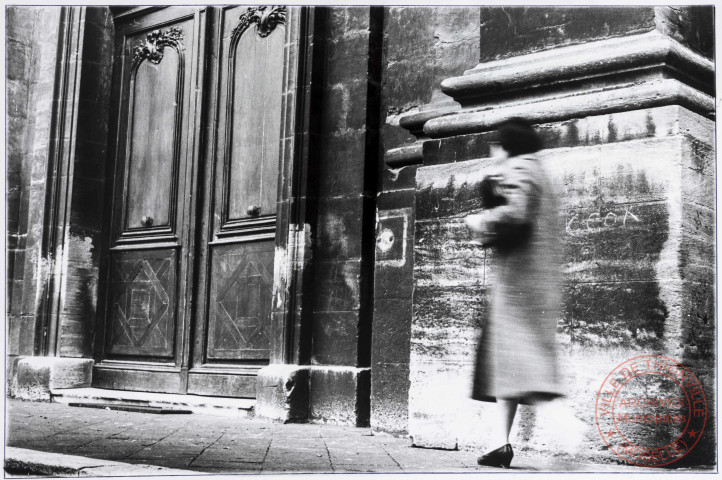 [Photo artistique d'une dame marchant devant l'église Saint-Maximin]