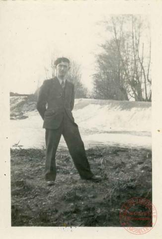 Portrait d'un homme en béret posant dans un écrin de verdure