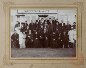[Photo de groupe réalisée lors d'un mariage (supposé) devant un bâtiment avec l'enseigne "WIRTSCHAFT" (entreprise)]
