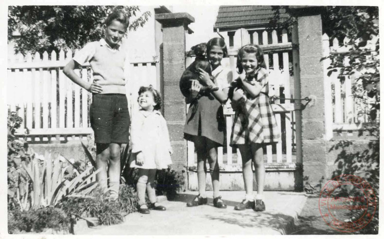 4 enfant et 1 chien posent dans la cour d'une maison