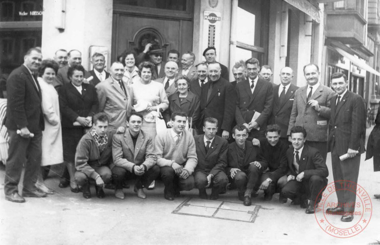 [Vin d'honneur, équipe sportive, échange de fanions et de cadeaux en salle des mariages et photo de groupe place du Marché]